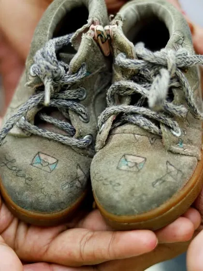 A close up shot focusing on a pair of tiny baby shoes held in the hands of the expectant parents, a classic and symbolic maternity photo.