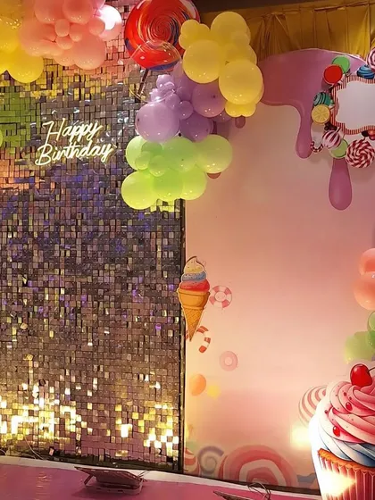 A detail shot of the Candyland theme, focusing on the shimmer wall, 'Happy Birthday' neon sign, and the large cupcake prop.