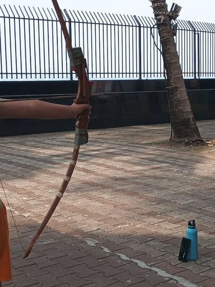 A close-up view of a student's grip and arrow placement on the bow.