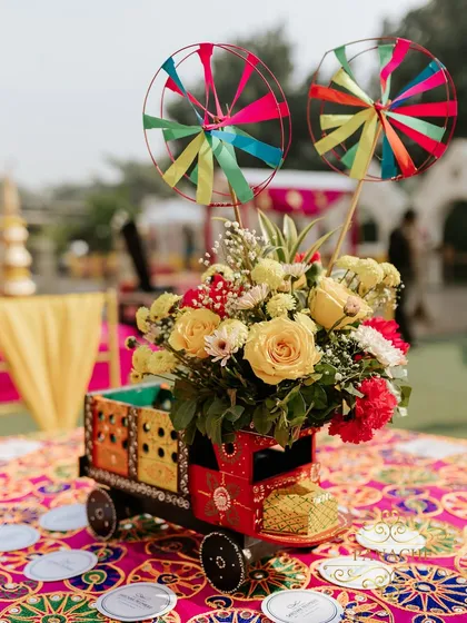 Another creative centerpiece designed in a miniature decorative truck, filled with yellow and red flowers. These unique details make the event memorable.