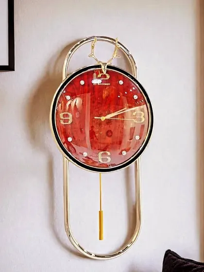 A bold and beautiful timepiece, this imported pendulum clock showcases a striking red-faced design. The combination of the vibrant color and the sleek golden frame creates a modern statement piece that is sure to draw attention.