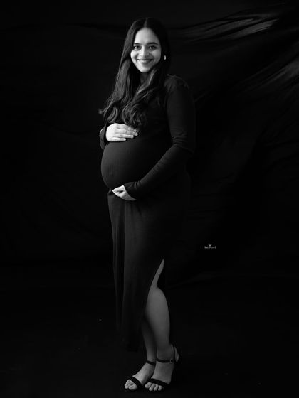 A classic and chic black and white portrait. The simple black dress and confident smile create a timeless and sophisticated look for this maternity photo.