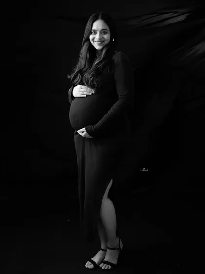 A classic and chic black and white portrait. The simple black dress and confident smile create a timeless and sophisticated look for this maternity photo.