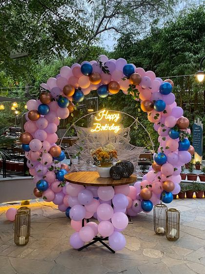 A beautiful outdoor birthday setup with a circular balloon arch in pink, purple, and blue.