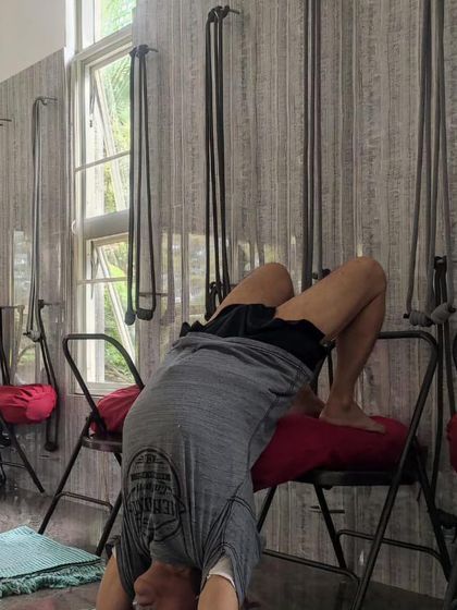 A supported backbend using a chair and wall ropes.