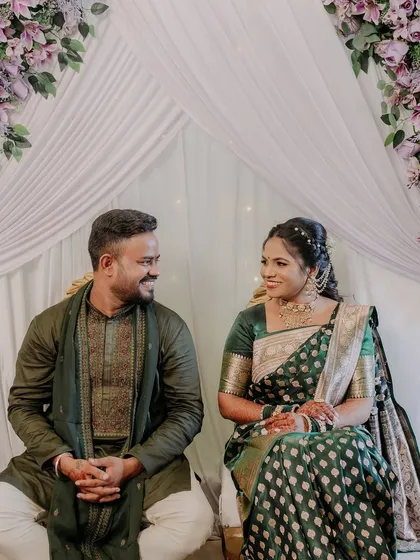 A lovely portrait of the newly engaged couple, seated together and sharing a happy, knowing smile.