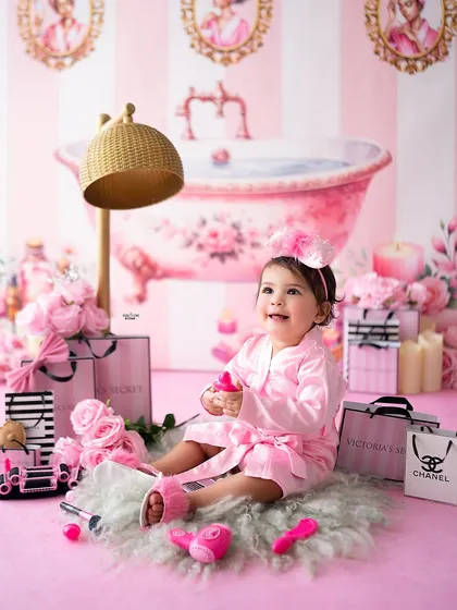 It's a spa day! This adorable baby is all smiles in her pink satin robe, surrounded by everything needed for a day of pampering. These creative sessions are always a hit.
