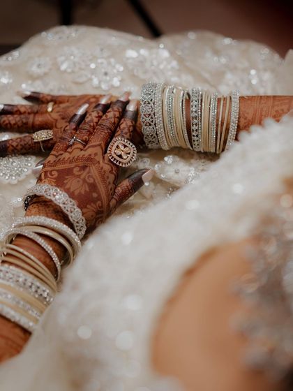 A close-up of the beautiful henna stain, adorned with sparkling bangles and rings. The dark color signifies deep love.