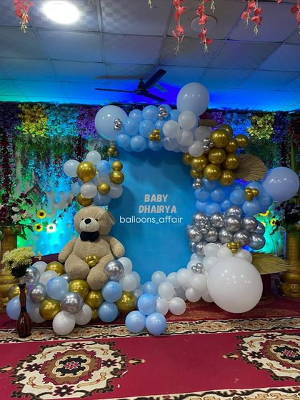 A detailed shot of the teddy bear themed stage decoration. The blue, white, silver, and gold balloons perfectly complement the central blue backdrop for 'Baby Dhairya'.