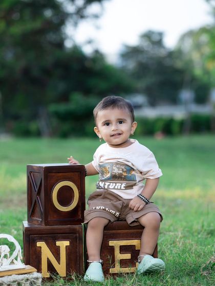 A happy one-year-old posing with his birthday blocks in the park.