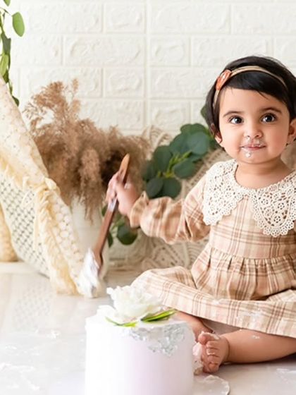 A playful moment captured as she digs into the cake with a wooden spoon during her first birthday session.