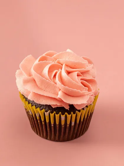 A classic rose swirl of pink vanilla buttercream tops this moist Belgian chocolate cupcake. It’s a timeless design that’s always in style.