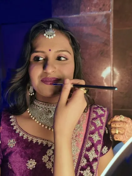 Here I am giving the final touches to Lakshmi's reception makeup. We chose a beautiful berry lip color to complement her rich purple lehenga and intricate silver jewelry.