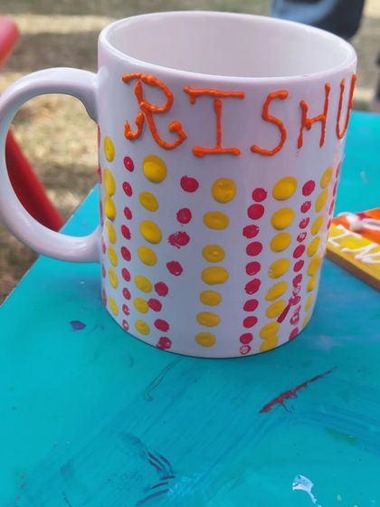 A close-up of a personalized mug, decorated with colourful dots and a name. This is a popular activity at my party stalls, as everyone loves having their own custom mug.