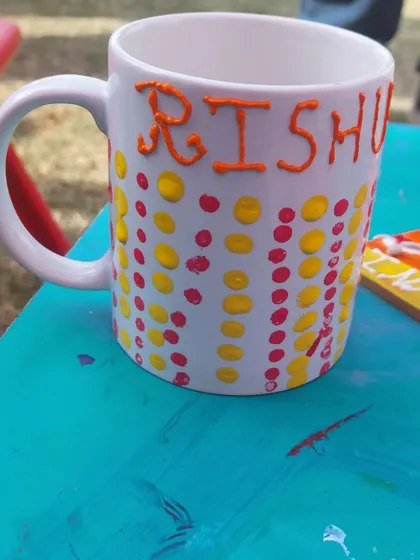A close-up of a personalized mug, decorated with colourful dots and a name. This is a popular activity at my party stalls, as everyone loves having their own custom mug.