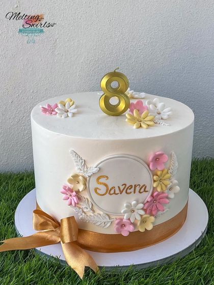 A beautiful spring-themed cake with a wreath of fondant flowers around the birthday girl's name. The soft colors and delicate details make this a very special design.