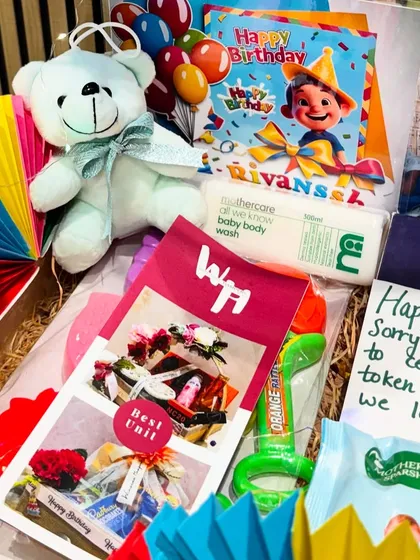 A close-up of the baby birthday hamper. You can see the cute teddy bear, personalized cards, and a mix of practical items like baby soap and fun toys.