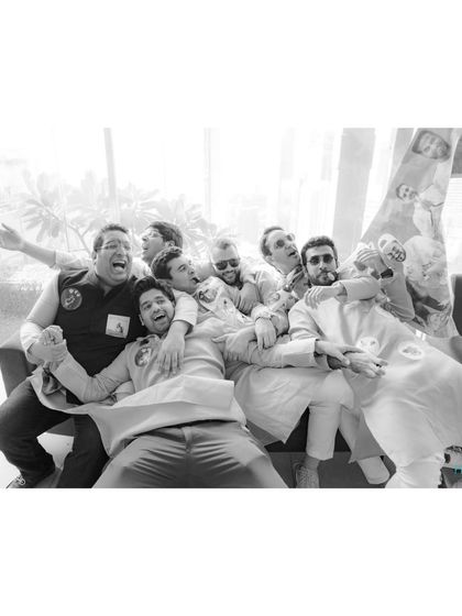 A chaotic and fun black and white shot of the groom and his friends piled onto a couch, capturing the madness of the celebration.