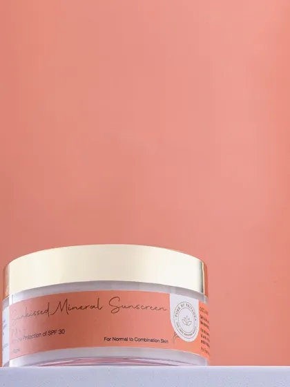 A minimalist shot of Pure by Priyanka's mineral sunscreen against a soft peach background. The clean composition highlights the product's elegant packaging.