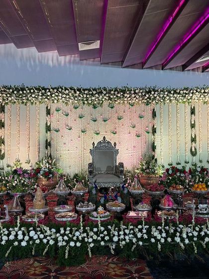 A stage with a white floral backdrop and hanging green amaranthus.