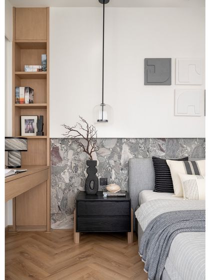 The master suite was enhanced by removing a powder bathroom, resulting in a spacious environment. The bed is framed by a stone backdrop, and a bespoke wooden study table with caldera stone legs adds a touch of sophistication.