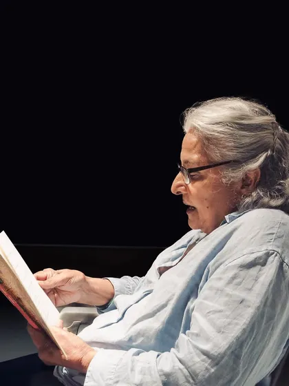 An audience member deeply engrossed in a book during a reading. This captures the quiet, personal side of our literary events.