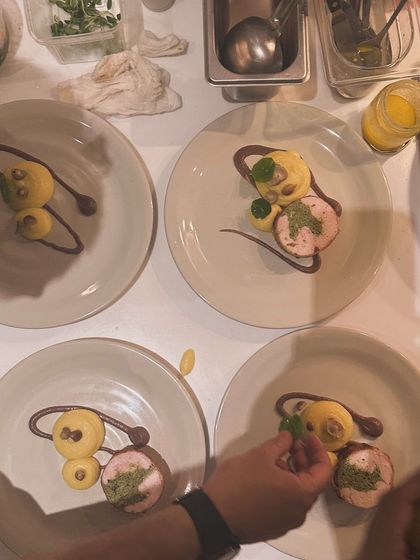 Plating the chicken ballotine with artistic swirls of sauce and carefully placed garnishes.
