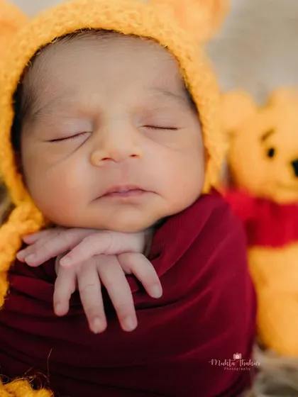 So tiny and precious. This newborn is perfectly snug in his red wrap, dreaming sweet dreams in his Winnie the Pooh themed photoshoot.