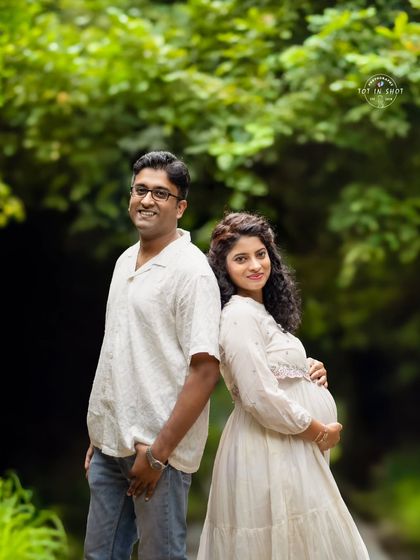 A sweet back-to-back pose of a couple in a natural, green setting, capturing their relaxed and happy connection.
