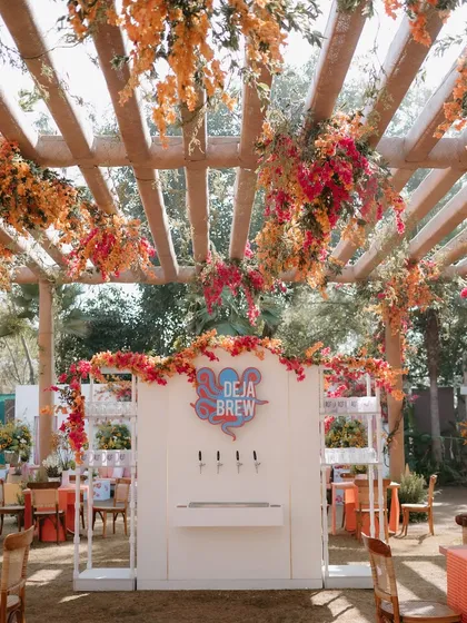 A carnival-themed Mehendi featuring a "Deja Brew" station with beer on tap, set under a pergola dripping with bougainvillea.
