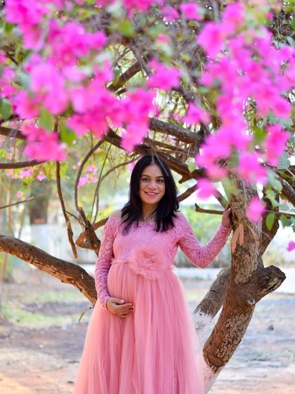 A beautiful portrait of a mom-to-be under a blooming bougainvillea tree. The pink of the gown and the flowers create a perfectly coordinated and stunning image.