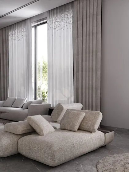 The low-slung, modular sofa provides ample, comfortable seating, perfect for a family lounge. Tall windows dressed in elegant grey curtains allow for plenty of natural light, making the space feel open and airy.
