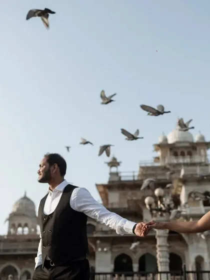 A dynamic shot of the couple walking hand-in-hand as pigeons take flight around them. This image captures the life and energy of Jaipur, making it a living part of their story.