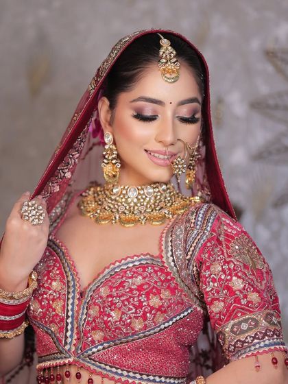 The perfect bridal pose. This look showcases a classic red lehenga with soft, shimmery eye makeup and a flawless base, creating a radiant and traditional aesthetic.