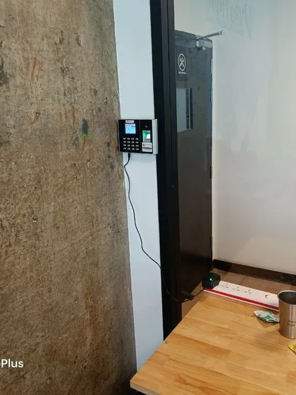 This shot shows the full setup of the biometric machine next to the office door, with the power adapter neatly connected.