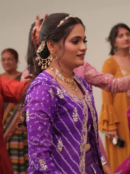 Feeling pretty in purple for a pre-wedding event. This candid shot captures the bride enjoying the festivities, with her hair in a soft half-up style and beautiful purple eye makeup.