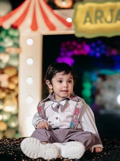 A sweet portrait of the birthday boy amidst the fun of his party. The bright lights and colorful decor of the carnival theme make a fantastic backdrop.