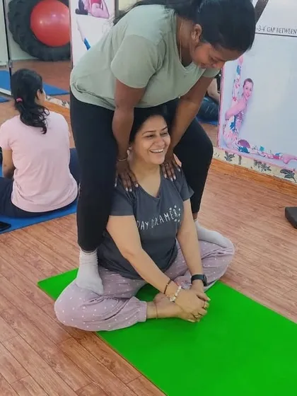 The joy of partner work in our studio. Here, one student gently assists another in Baddha Konasana (Butterfly Pose), helping to deepen the hip-opening stretch while sharing a smile.