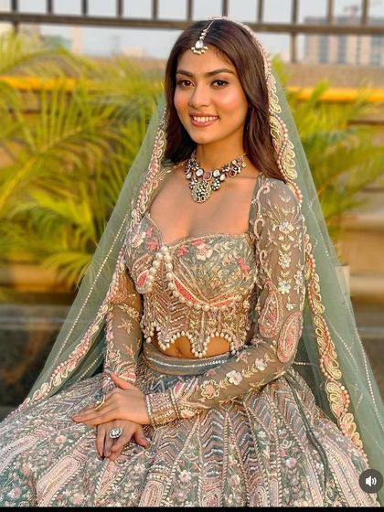 A smiling bride-to-be in our pastel green and pink lehenga. The sheer dupatta with an embroidered border adds a final touch of elegance.