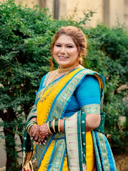 A beautiful portrait of the bride in her vibrant yellow and blue saree. The makeup is kept fresh and glowing to match the celebratory feel of the occasion.