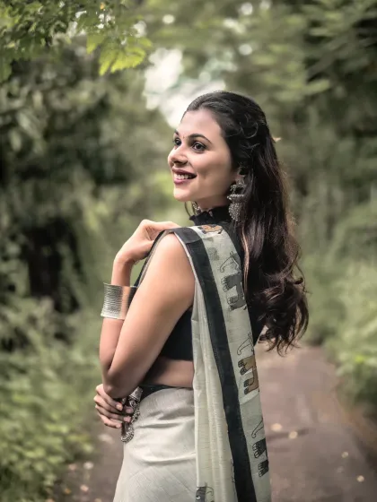 A moment of classic elegance. This outdoor portrait captures a modern woman in a traditional saree, using soft natural light to create a timeless and serene image against a lush green backdrop.