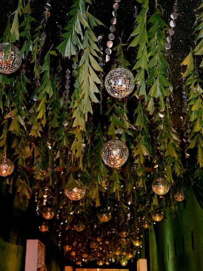 A ceiling decorated with hanging greenery and disco balls, creating a magical, forest-like party atmosphere.