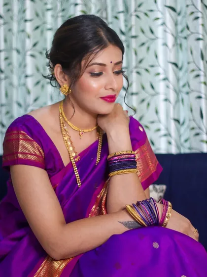 A candid moment showing the complete look, from the messy bun hairstyle to the vibrant makeup and traditional bangles.