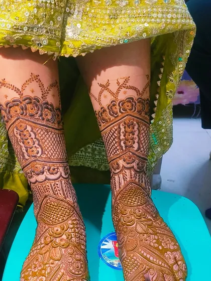 A full bridal foot mehandi design that extends up the legs. The pattern is dense and intricate, perfect for a bride.