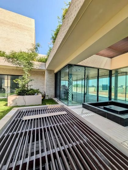The courtyard of the Dubai Hills villa, showing the water body and the connection to the interior spaces through large glass walls.