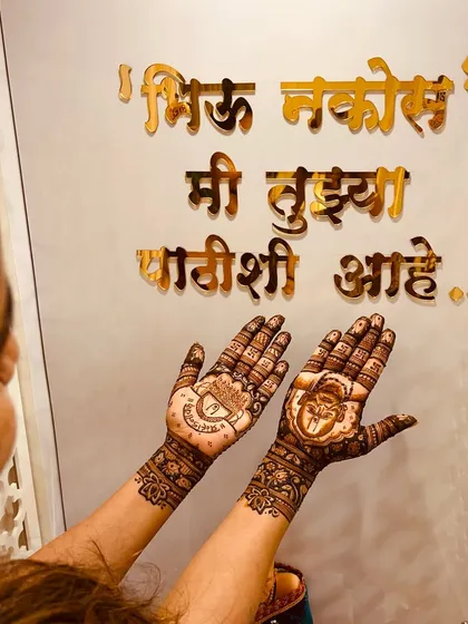 A client displaying her spiritual mehendi in front of the reassuring words 'Bhiu Nakos, Mi Tujhya Pathishi Aahe'. The design features a portrait of Swami Samarth.