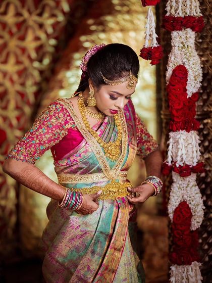 Another angle of the bride adjusting her waist belt (vaddanam), showing the full splendor of the bridal attire.