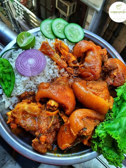 A hearty dish of pork leg cooked with bamboo shoots and fermented soybeans, garnished with fresh herbs.