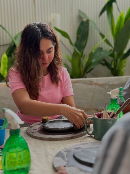 A student working on her piece amidst the lush greenery of a cafe setting. The atmosphere is always relaxed and inspiring.