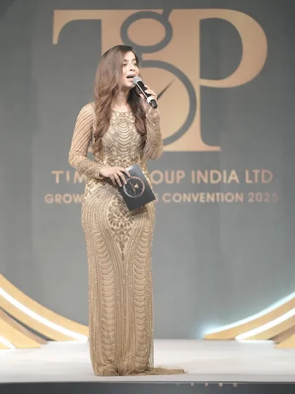 Holding the event booklet while addressing the audience at the Timex convention.